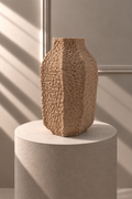 Jarrón Arena Texturizado de forma alta y escultórica, con superficie rugosa en relieve y paneles verticales.