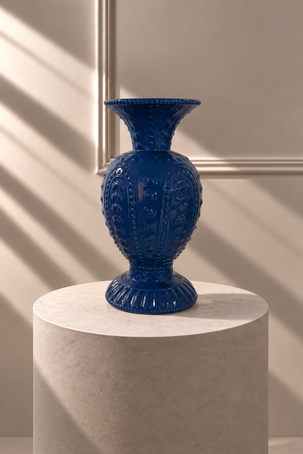 Jarrón Azul Palacio de EDG sobre pedestal, con silueta alta y relieves ornamentales en azul intenso.