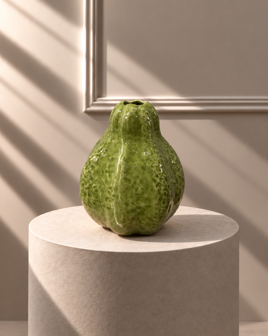 Jarrón Guayaba Verde sobre pedestal, con forma orgánica redondeada y superficie texturizada en tonos verdes.