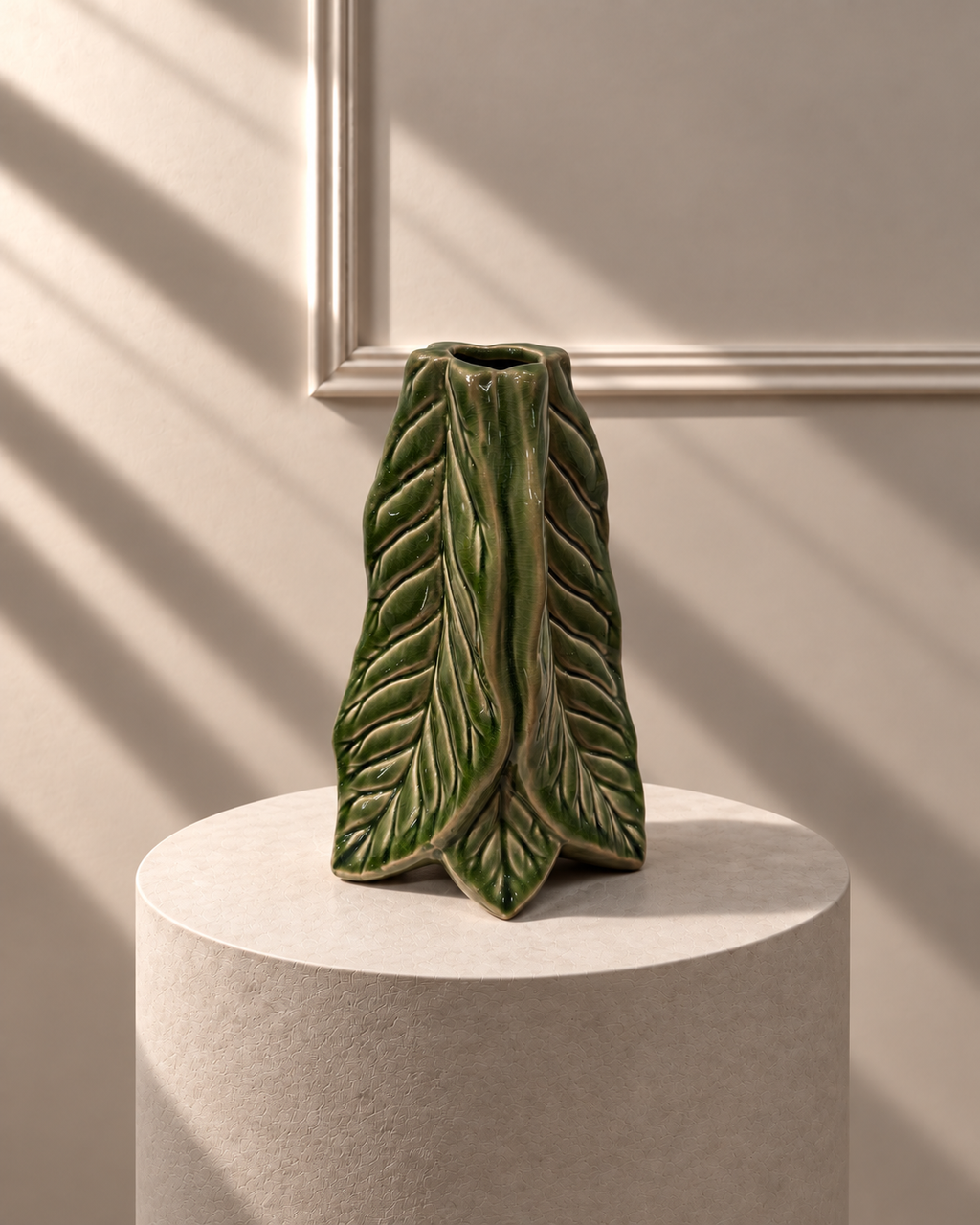 Jarrón Hoja Verde sobre pedestal, con forma escultórica de hoja plegada y esmalte verde brillante.

