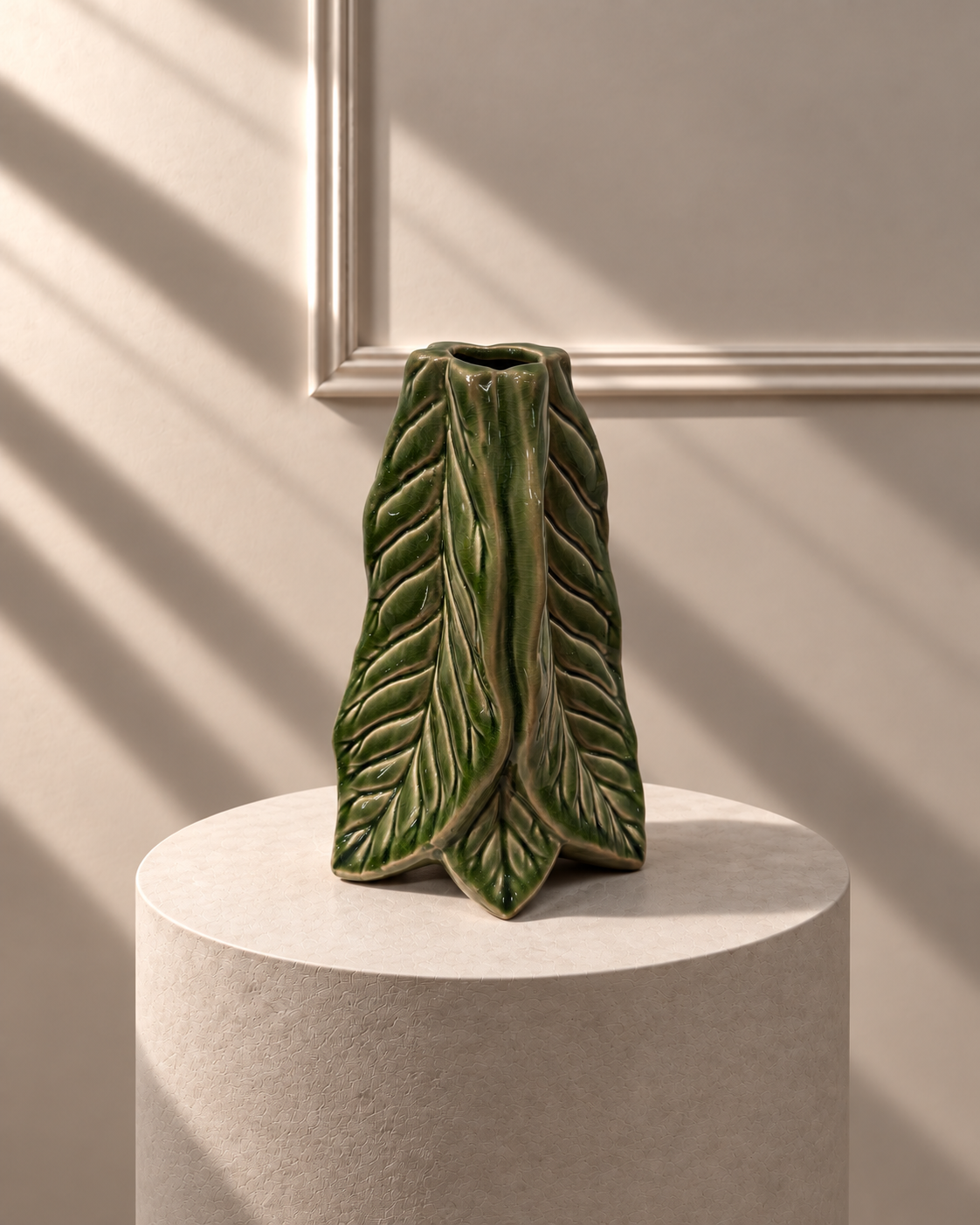 Jarrón Hoja Verde sobre pedestal, con forma escultórica de hoja plegada y esmalte verde brillante.
