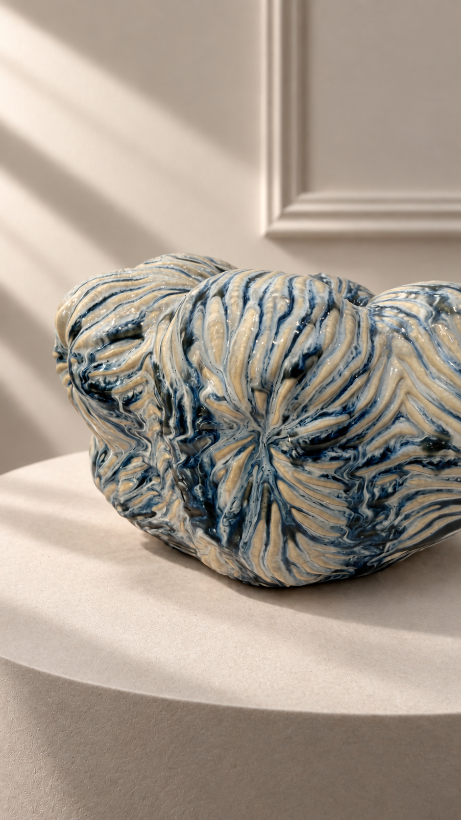 Jarrón Oceana Pequeño azul y blanco sobre pedestal, con forma baja y relieve orgánico en toda la superficie.