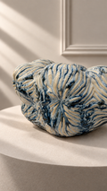 Jarrón Oceana Pequeño azul y blanco sobre pedestal, con forma baja y relieve orgánico en toda la superficie.