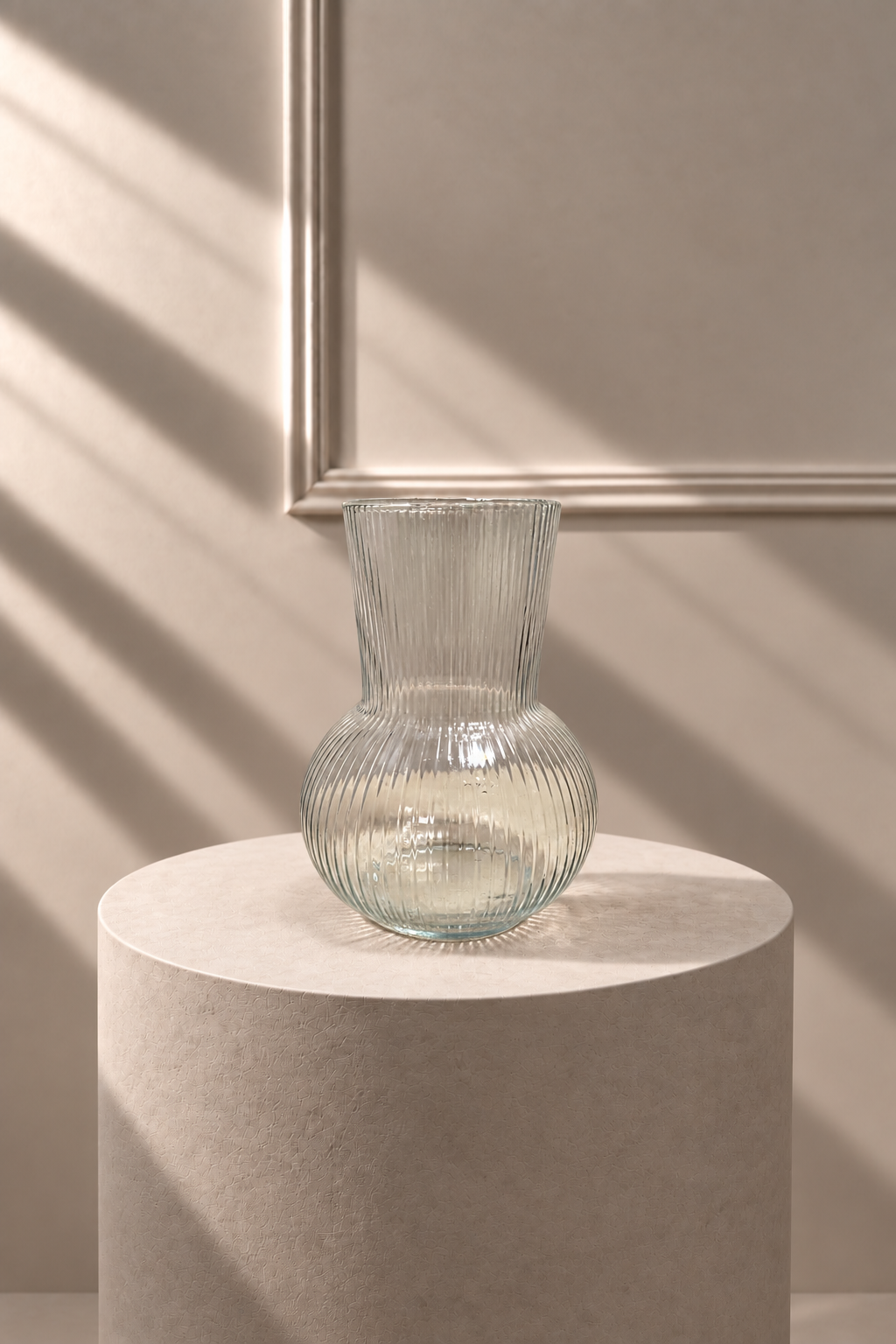 Jarrón de Vidrio Acanalado transparente con cuerpo redondeado y relieve vertical, sobre pedestal de piedra
