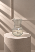 Jarrón de Vidrio Acanalado transparente con cuerpo redondeado y relieve vertical, sobre pedestal de piedra