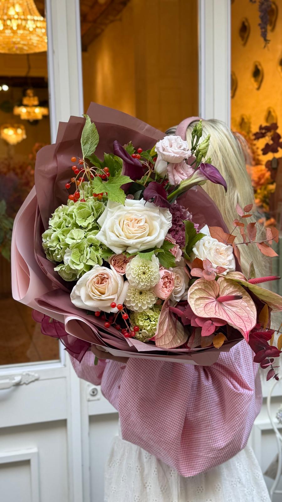 Ramo Rosa Antigua con rosas crema y rosa suave, hortensias verdes, lisianthus rosa, calas burdeos, anturios rosados, flores crema, bayas rojas y follaje de eucalipto, envuelto en papel rosa envejecido y burdeos.