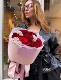 Ramo Rosa Roja Signature con rosas rojas intensas y flor de arroz blanca (Ozothamnus), envuelto en papel rosa y sostenido por una mujer.