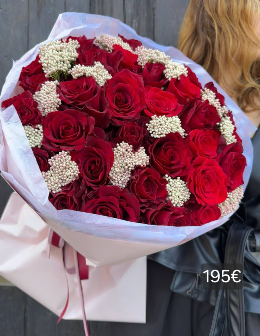 Ramo Rosa Roja Signature XL con 31 rosas rojas intensas y flor de arroz blanca (Ozothamnus), en una composición abundante y envuelta en papel rosa claro.